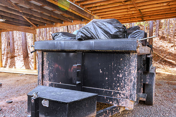 black dumpster is located under wooden shelter it is filled with garbage bags
